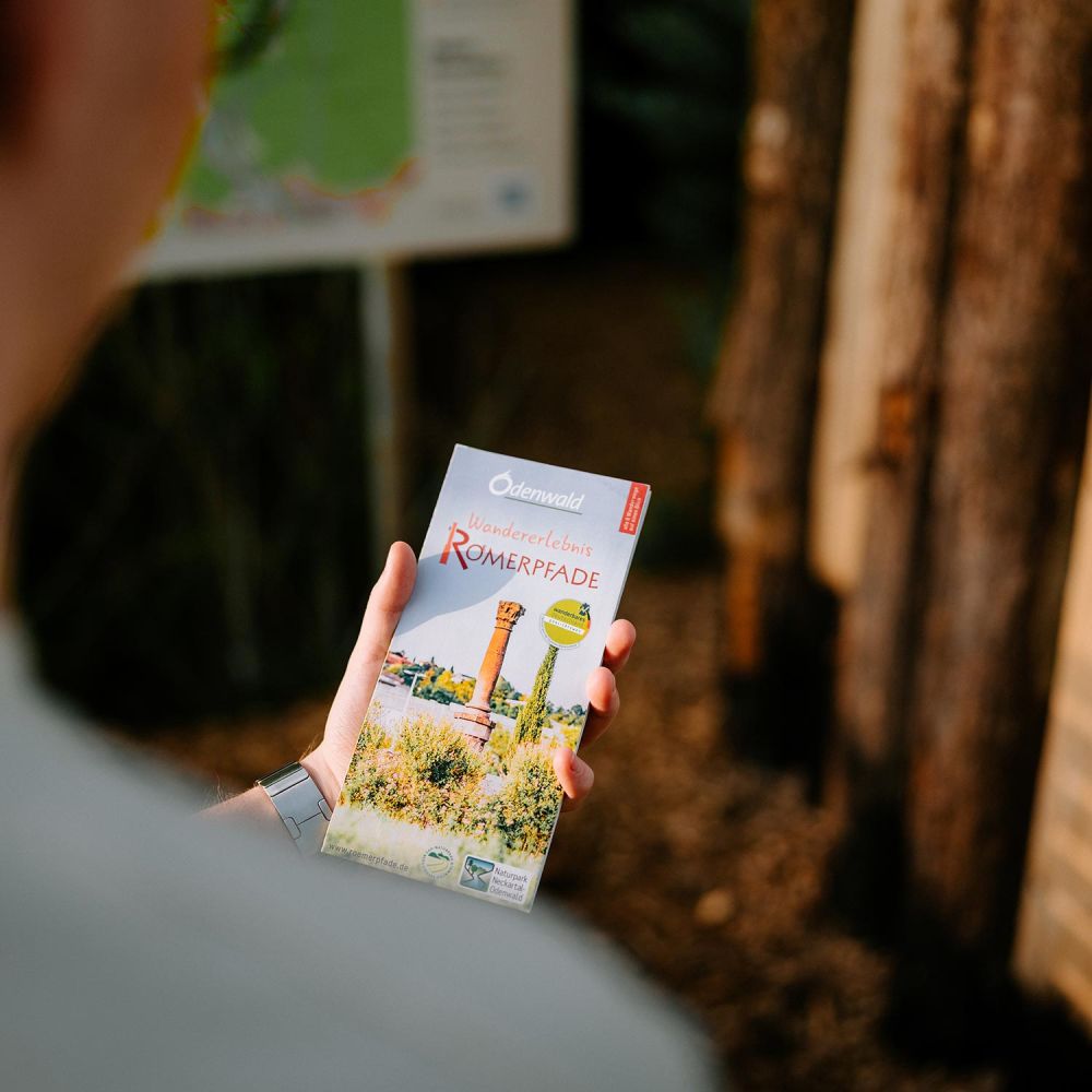 Mann hält Römerpfade Karte zusammengeklappt in der Hand