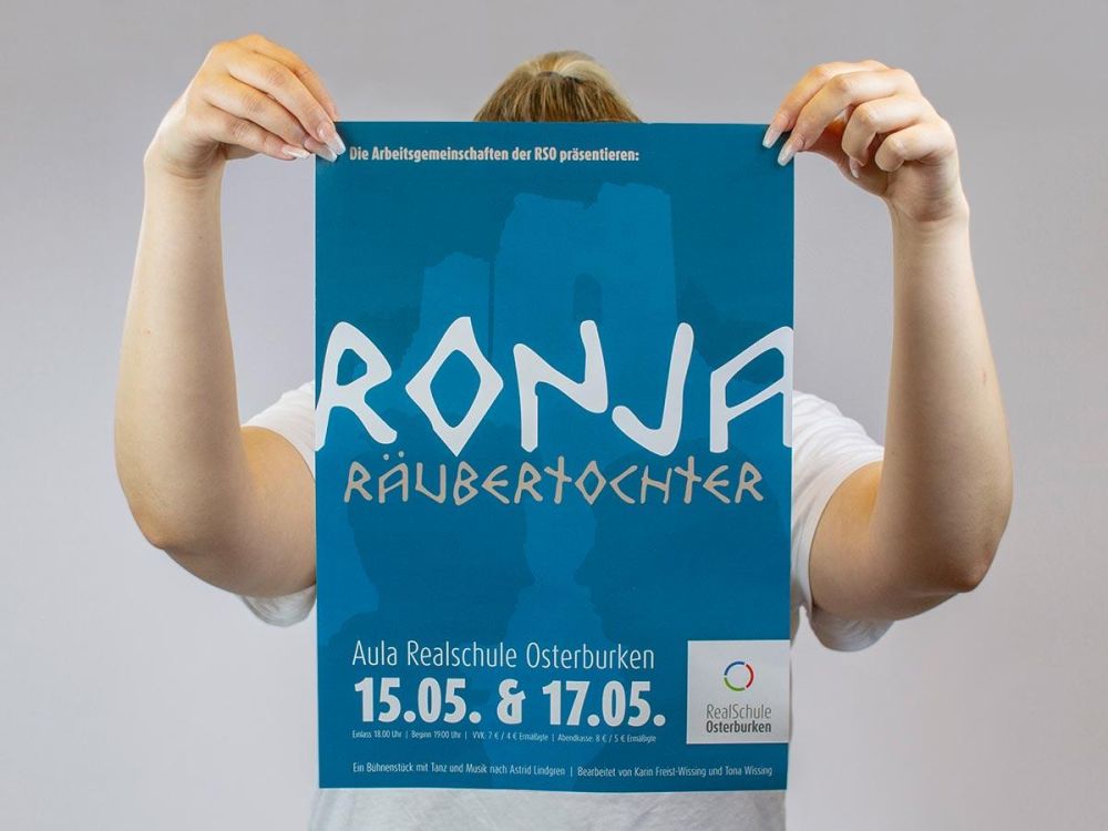 Plakat Ronja Räubertochter wird von blonder Person hochgehoben